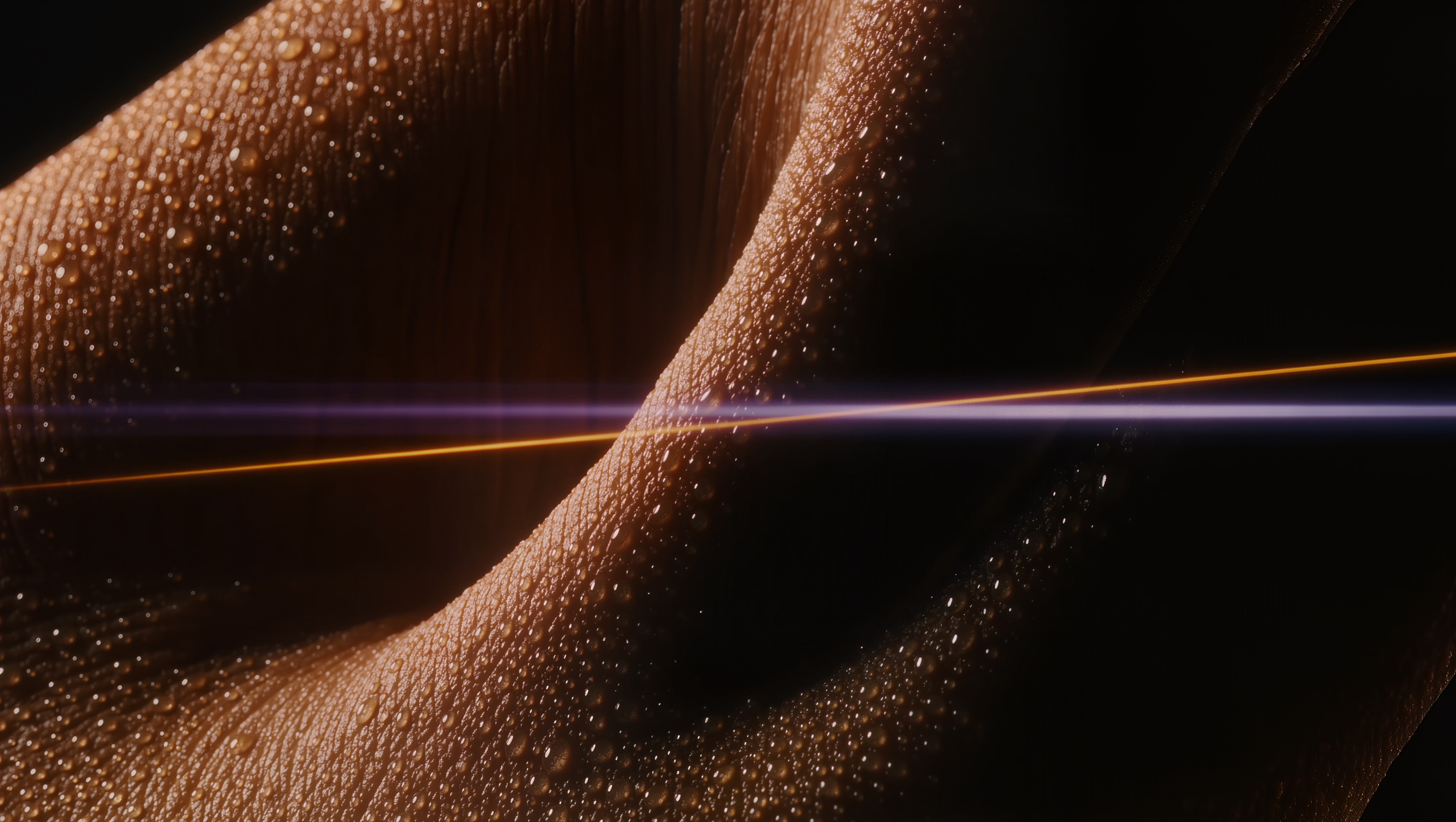 Abstract close-up of skin with beads of sweat, cut by a streak of amber and violet light